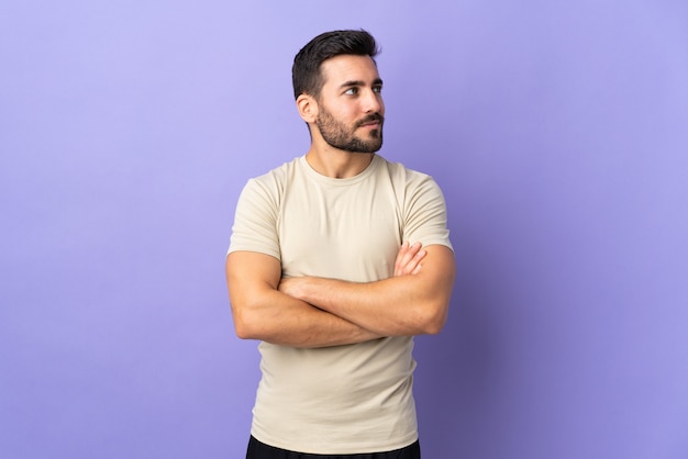 Hombre guapo joven con barba sobre fondo aislado mirando hacia el lado