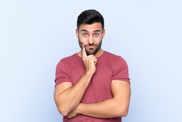 Foto hombre guapo joven con barba sobre fondo azul aislado mirando al frente