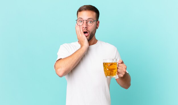 Hombre guapo joven bebiendo una pinta de cerveza