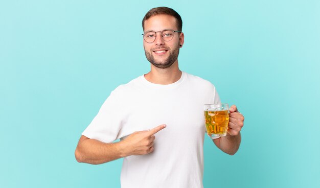 Hombre guapo joven bebiendo una pinta de cerveza