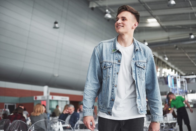 Hombre guapo joven con una bolsa en el hombro a toda prisa hacia el aeropuerto.