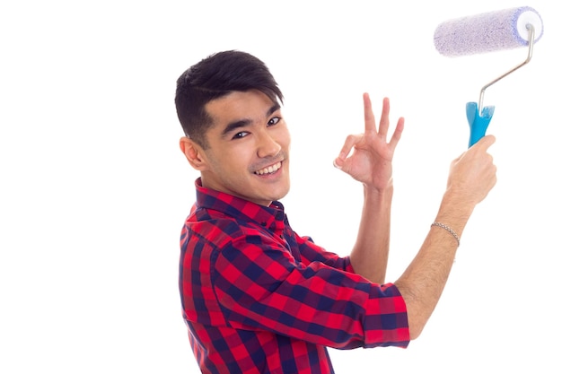 Foto hombre guapo joven con cabello oscuro en camisa a cuadros roja con rollo azul y mostrando bien en estudio