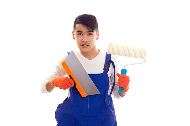 Hombre guapo joven con camisa blanca y azul en general con guantes naranjas sosteniendo espátula y rollo