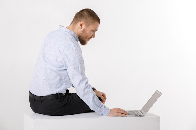 Hombre guapo joven en camisa y corbata usando laptop