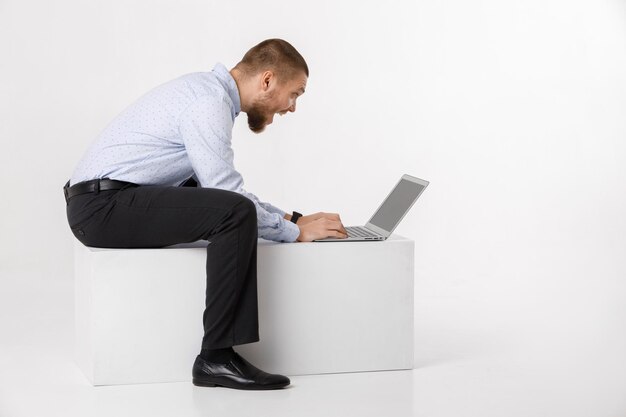 Hombre guapo joven en camisa y corbata usando laptop