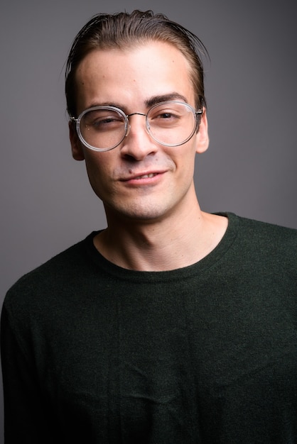 Hombre guapo joven con camisa de manga larga verde sobre gris