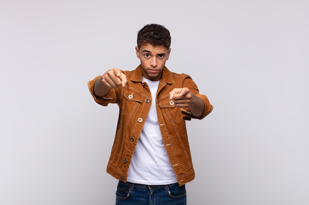 Foto hombre guapo joven con camisa de mezclilla marrón posando en la pared blanca