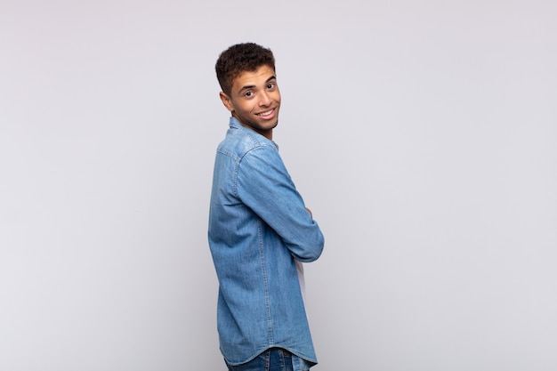 Hombre guapo joven con camisa de mezclilla posando en la pared blanca