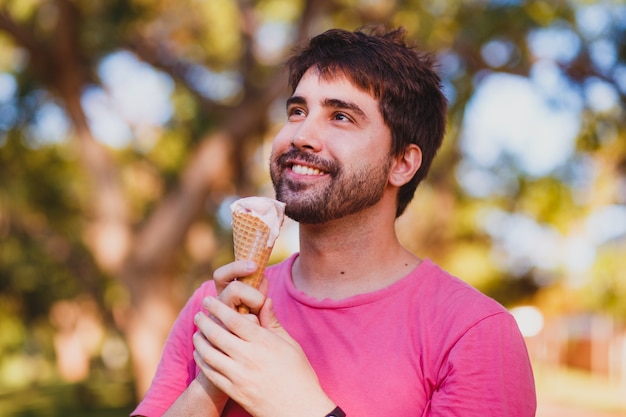 Hombre guapo joven comiendo helado en el parque