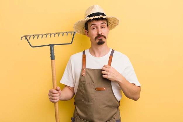 Hombre guapo joven con un concepto de granjero de rastrillo