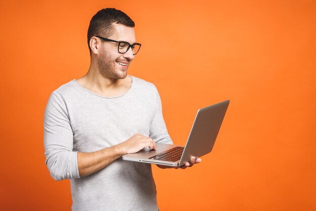 Foto hombre guapo joven confiado en casual celebración portátil y sonriendo