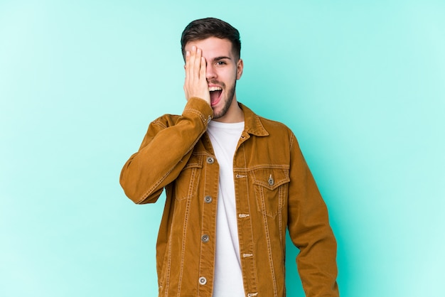 Hombre guapo joven divirtiéndose cubriendo la mitad de la cara con la palma.