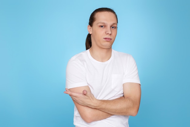 Hombre guapo joven con una duda en su rostro en camiseta aislada sobre fondo azul.