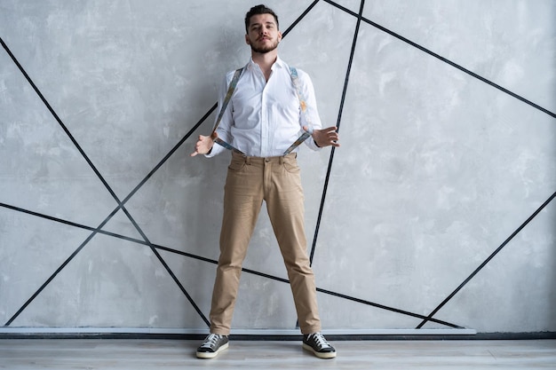 Hombre guapo joven elegante. Apuesto joven de pie contra el fondo gris