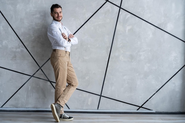 Hombre guapo joven elegante. Apuesto joven de pie contra el fondo gris