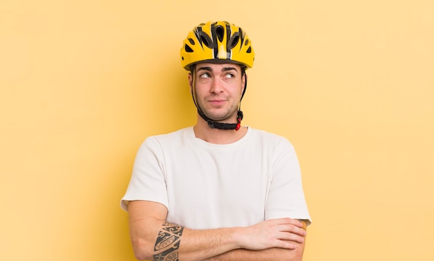 Hombre guapo joven encogiéndose de hombros sintiéndose confuso e incierto concepto de bicicleta