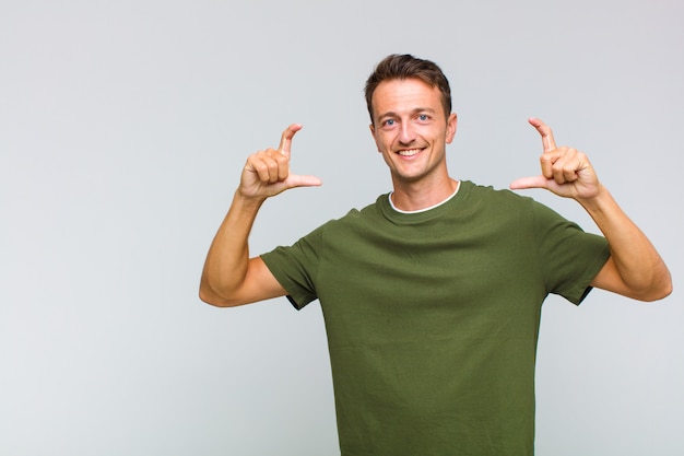 Hombre guapo joven enmarcando o delineando su propia sonrisa con ambas manos, luciendo positivo y feliz, concepto de bienestar