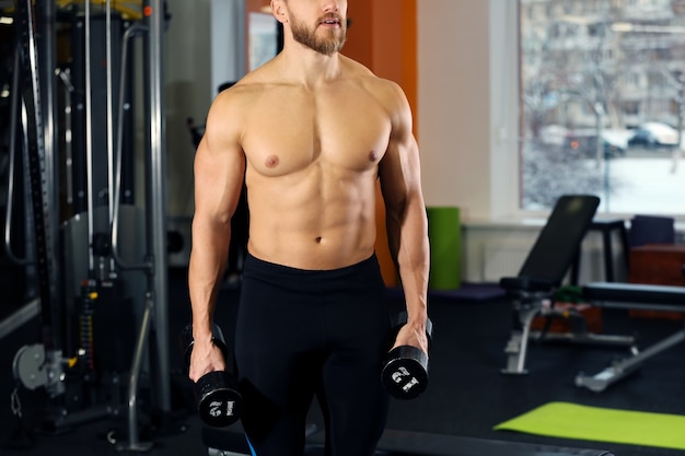 Hombre guapo joven con entrenamiento de pesas en el gimnasio