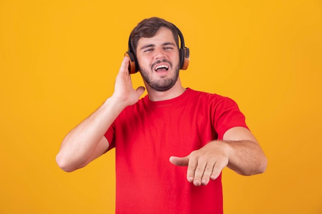 Hombre guapo joven escuchando música en auriculares fondo de estudio amarillo aislado sonriendo feliz