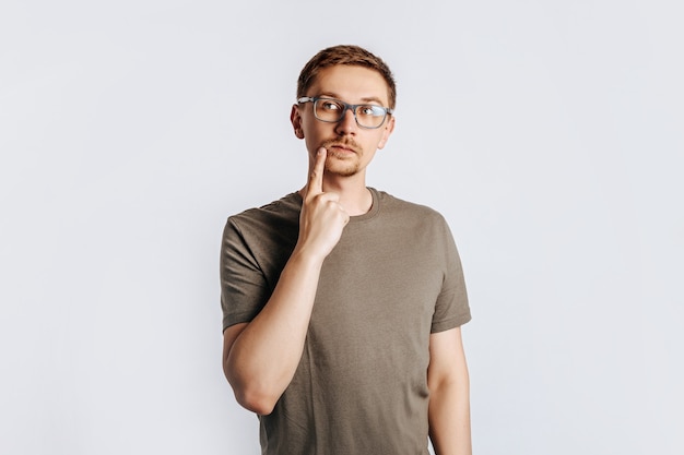 Hombre guapo joven con gafas una barba morena sobre fondo gris aislado