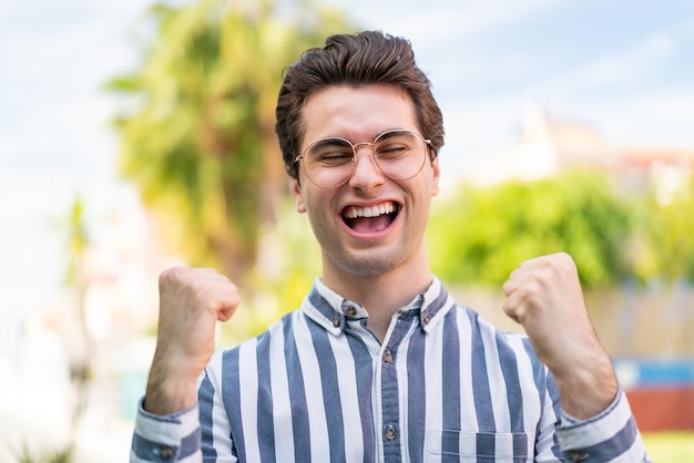 Foto hombre guapo joven con gafas y celebrando una victoria