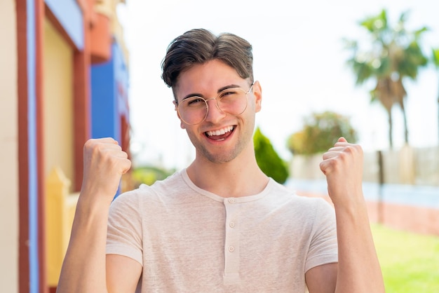 Hombre guapo joven con gafas y celebrando una victoria