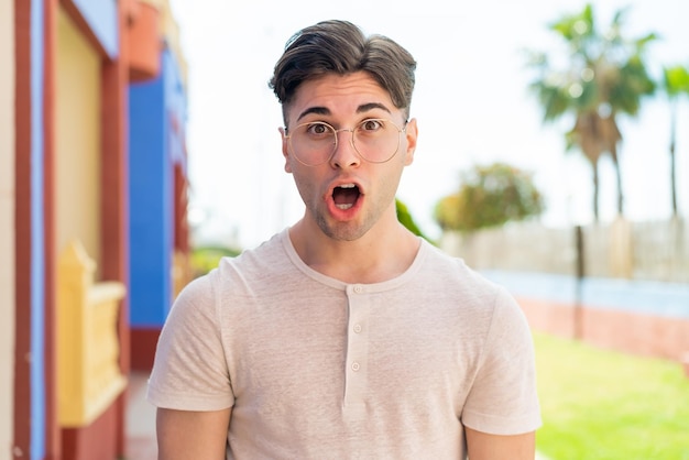 Hombre guapo joven con gafas y expresión sorprendida