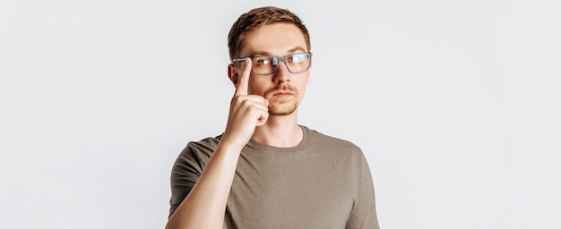 Hombre guapo joven con gafas piensa sobre fondo gris aislado