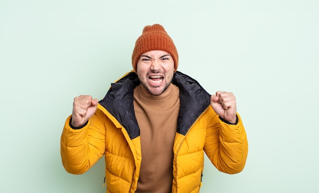 Hombre guapo joven gritando agresivamente con una expresión enojada. concepto de clima frío