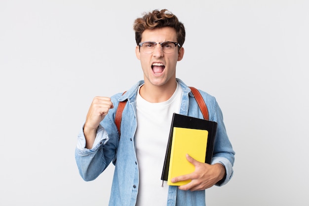 Hombre guapo joven gritando agresivamente con una expresión enojada. concepto de estudiante universitario