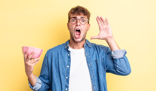 Hombre guapo joven gritando con las manos en el aire. concepto de cuenco vacío