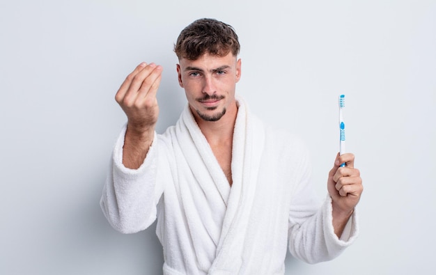 Hombre guapo joven haciendo capice o gesto de dinero, diciéndole que pague. concepto de cepillo de dientes