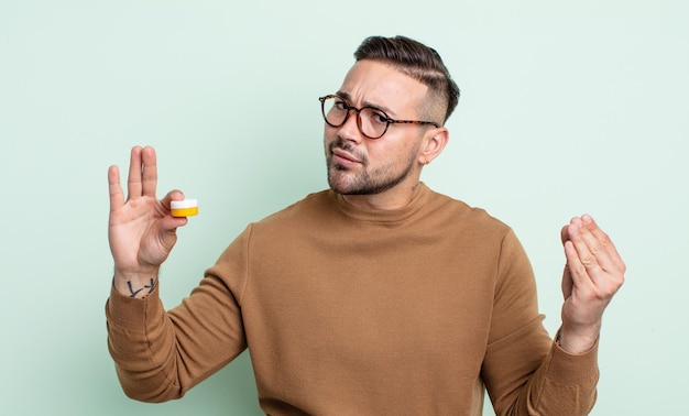 Hombre guapo joven haciendo capice o gesto de dinero diciéndote que pagues lentes de contacto