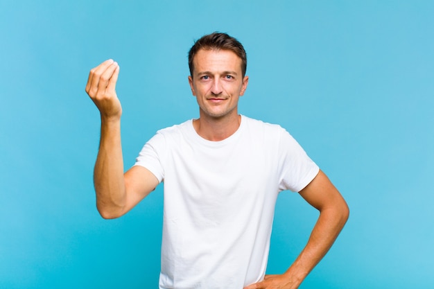 Hombre guapo joven haciendo capice o gesto de dinero