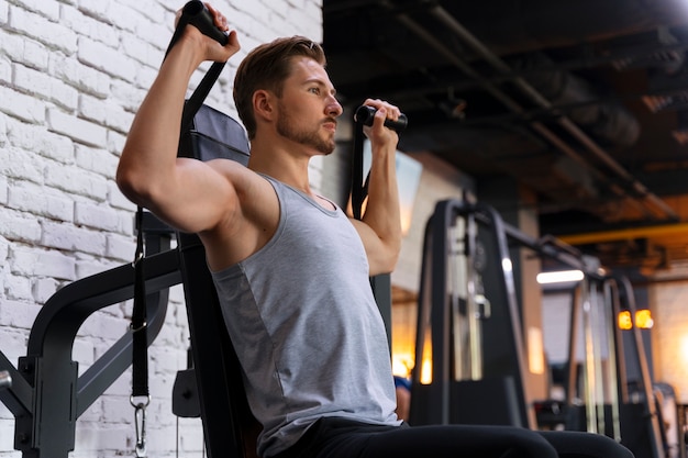 Hombre guapo joven haciendo ejercicio en el gimnasio para culturismo