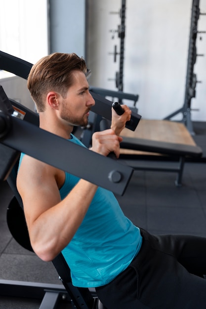 Foto hombre guapo joven haciendo ejercicio en el gimnasio para culturismo