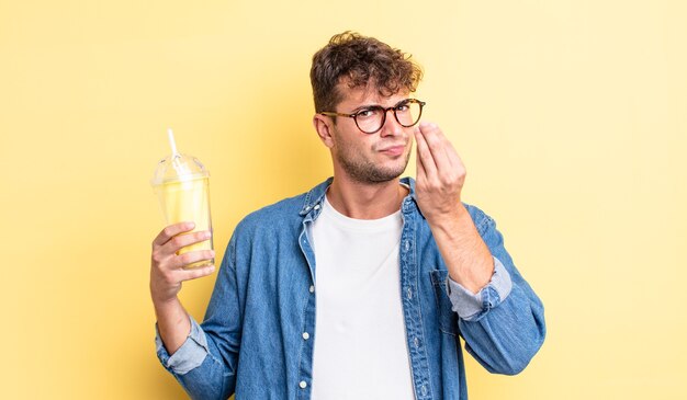 Hombre guapo joven haciendo gesto de capice o dinero, diciéndole que pague. concepto de batido