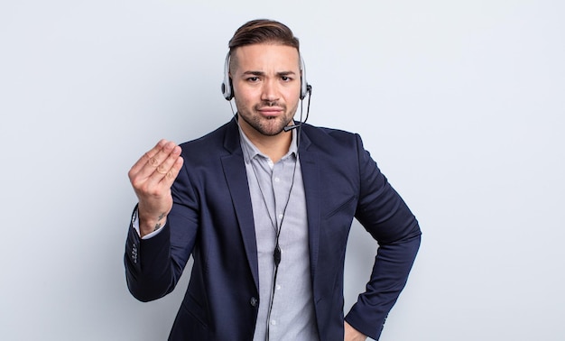 Hombre guapo joven haciendo gesto de capice o dinero, diciéndole que pague. concepto de telecomercialización