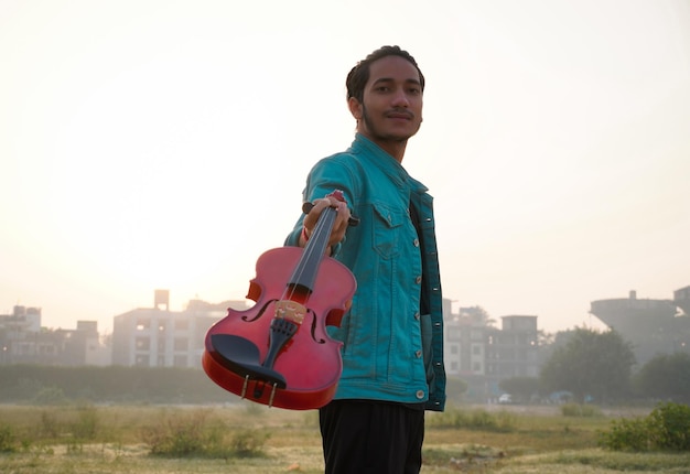 Hombre guapo joven indio mostrando violín