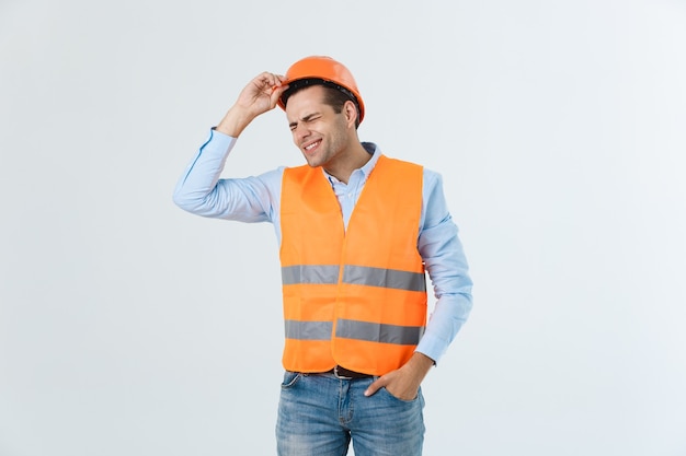 Hombre guapo joven ingeniero sobre fondo blanco con casco de seguridad con cara seria y mano conmocionada con vergüenza por error, expresión de miedo, asustado en silencio, concepto secreto