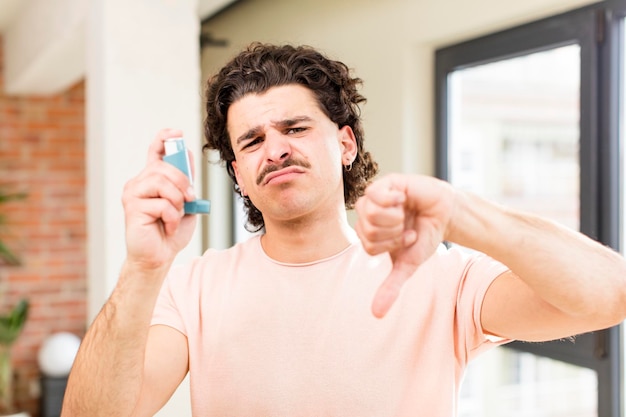 Hombre guapo joven con un inhalador de asma en el interior de su casa