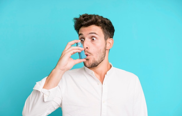 Hombre guapo joven con un inhalador de asma