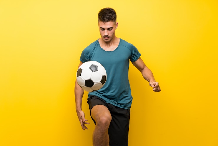 Foto hombre guapo joven jugador de fútbol sobre fondo amarillo aislado