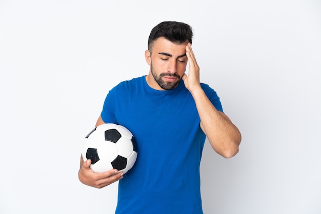 Hombre guapo joven jugador de fútbol sobre pared aislada con dolor de cabeza