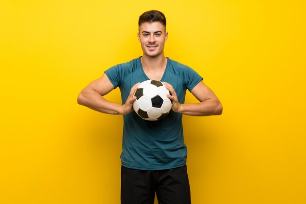 Foto hombre guapo joven jugador de fútbol sobre pared amarilla aislada