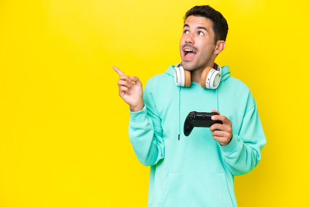 Hombre guapo joven jugando con un controlador de videojuego sobre una pared aislada con la intención de darse cuenta de la solución mientras levanta un dedo