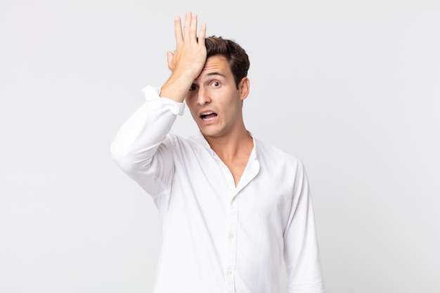 Hombre guapo joven levantando la palma de la mano a la frente pensando ¡Uy, después de cometer un error estúpido o recordar, sentirse tonto!