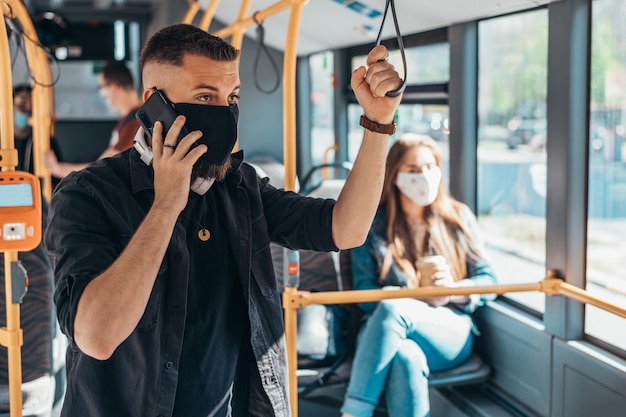 Hombre guapo joven con máscara protectora y usando su teléfono inteligente