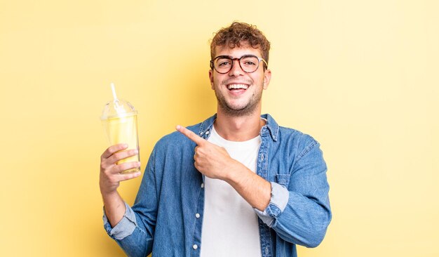 Hombre guapo joven mirando emocionado y sorprendido apuntando hacia un lado. concepto de batido