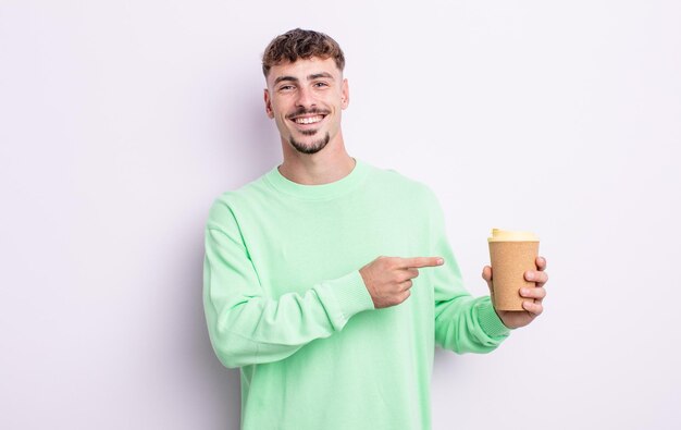 Hombre guapo joven mirando emocionado y sorprendido apuntando hacia un lado. concepto de café para llevar